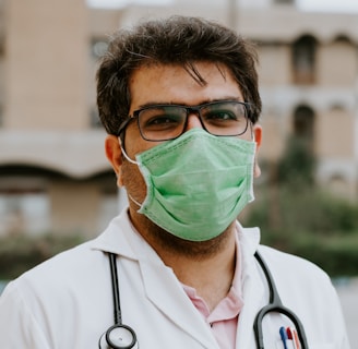 man in white scrub suit wearing green mask