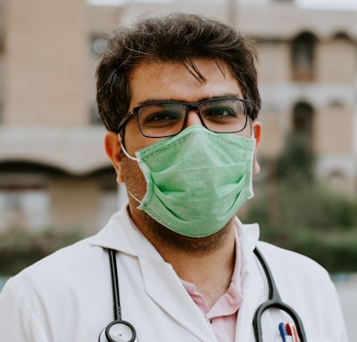 man in white scrub suit wearing green mask