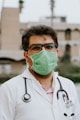 man in white scrub suit wearing green mask