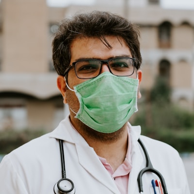 man in white scrub suit wearing green mask