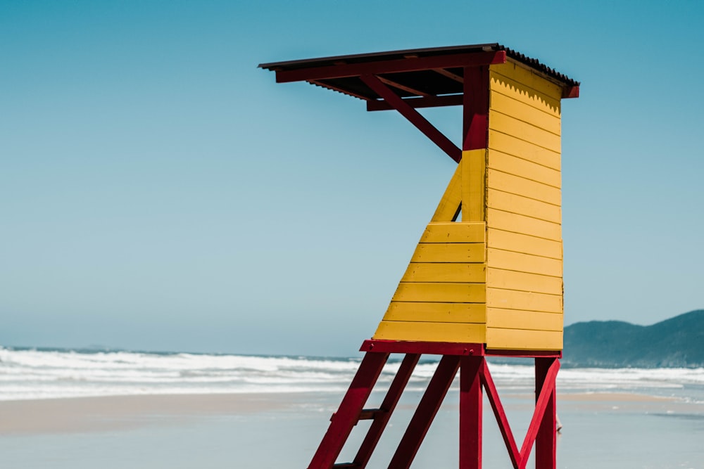 yellow wooden lifeguard tower on beach during daytime