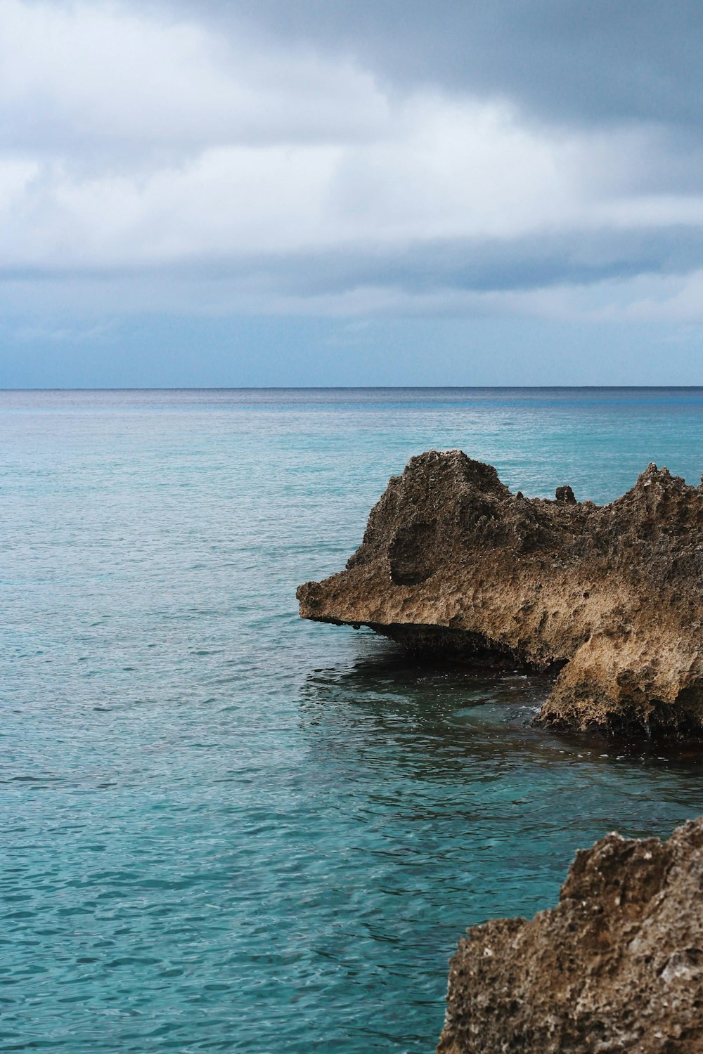 brown rock formation on sea under blue sky during daytime