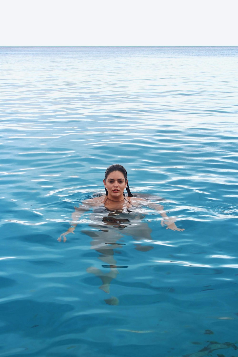 femme en bikini bleu et blanc nageant dans la mer pendant la journée