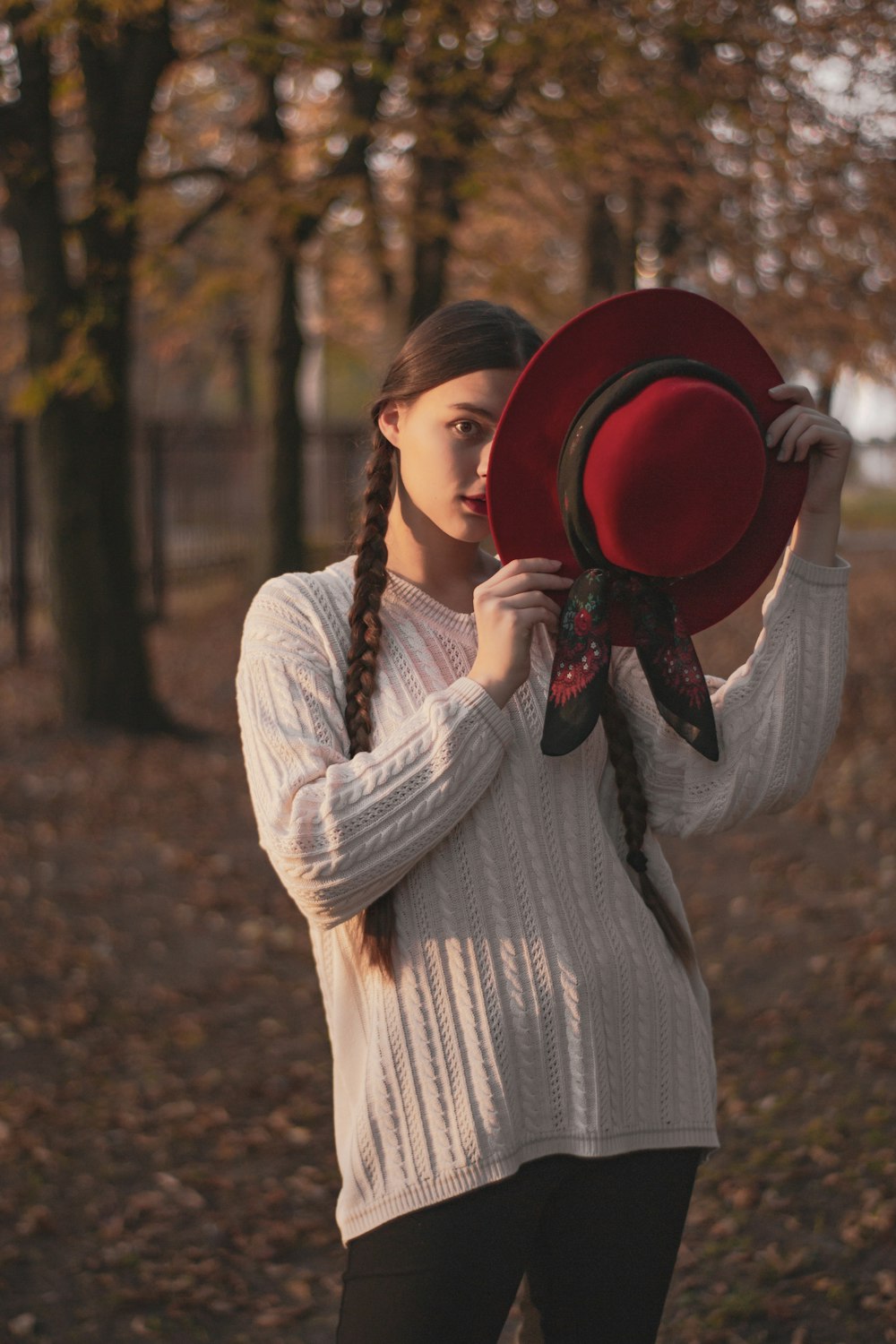 woman in white long sleeve dress holding red hat