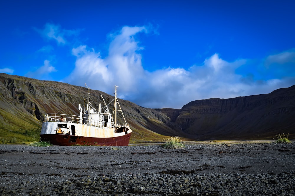 weißes und braunes Boot auf grauem Sand tagsüber