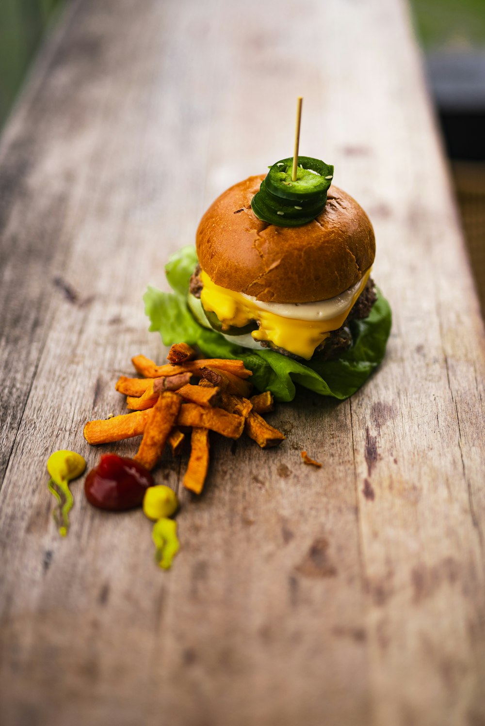 burger with lettuce and fries on brown wooden table