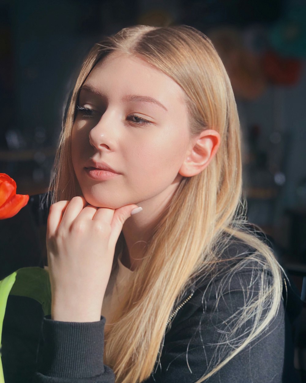 girl in black and green long sleeve shirt holding red flower