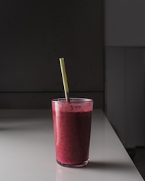 pink liquid in clear drinking glass with green straw