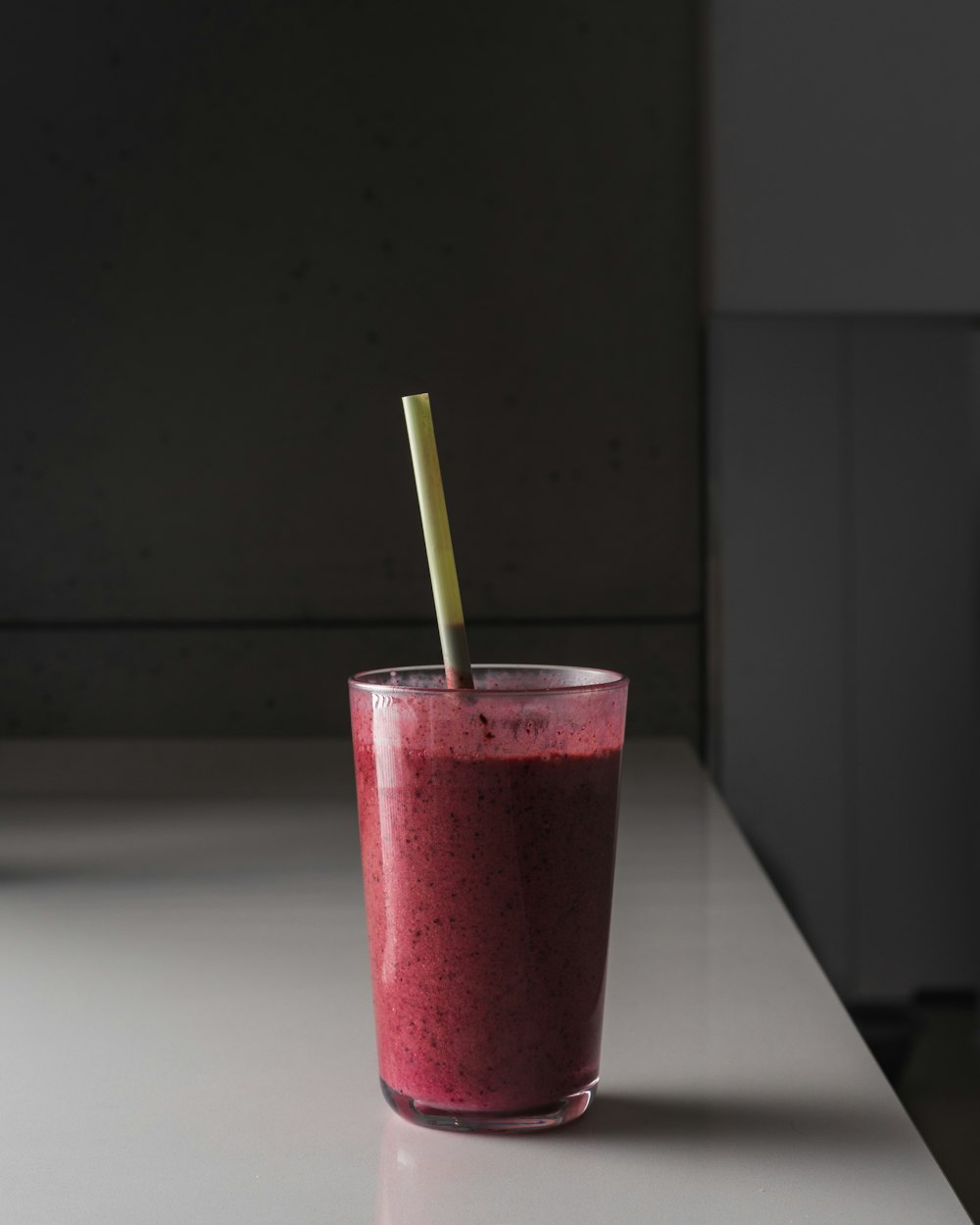 pink liquid in clear drinking glass with green straw