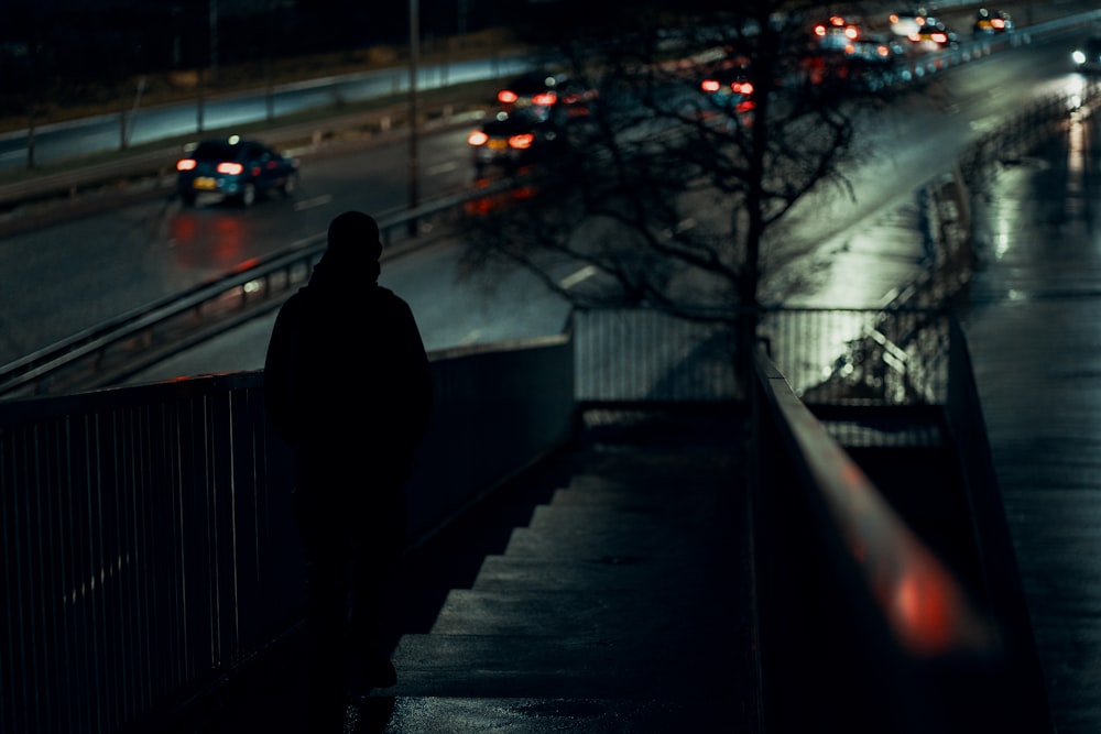 man in black coat standing on sidewalk during night time