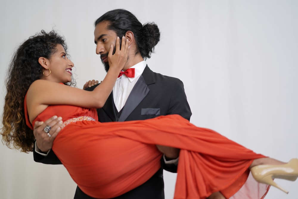 man in black suit kissing woman in red dress