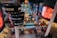 An indoor theme park with vibrant, colorful lights and signage. The neon lights are abundant, featuring circular screens displaying advertisements. A large sign reads 'Skytropolis Indoor Theme Park' surrounded by various attractions including a Ferris wheel.