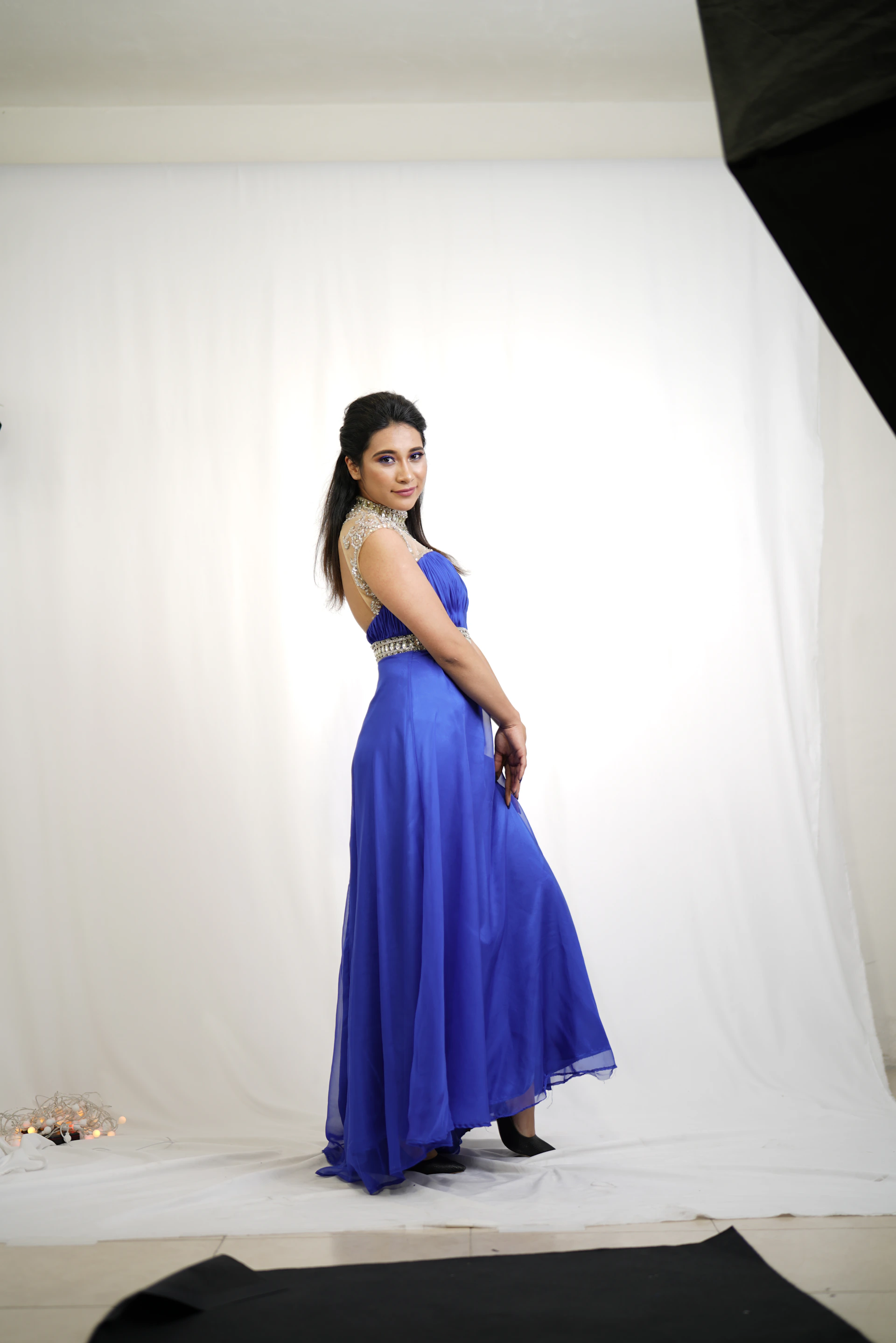 A sophisticated anarkali gown blending classic and modern styles in a flowing cream fabric with subtle shimmer, styled in a bright, airy studio setting.