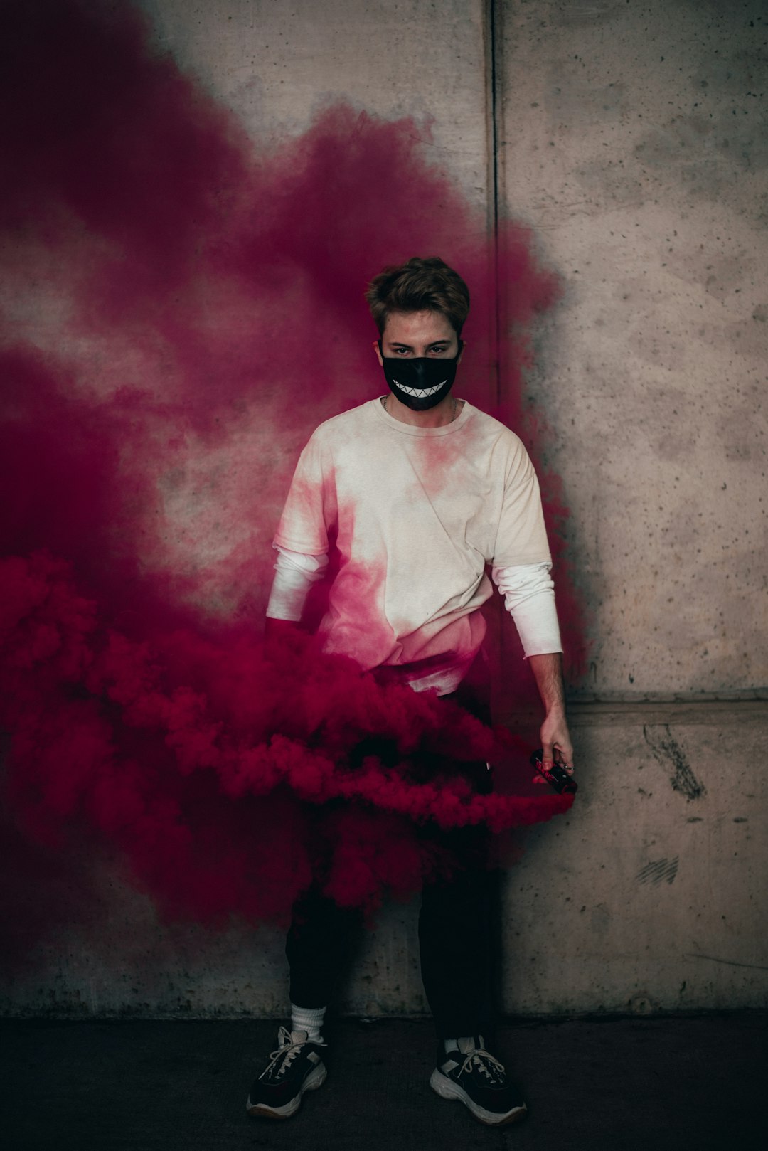 man in white long sleeve shirt and red skirt sitting on concrete wall