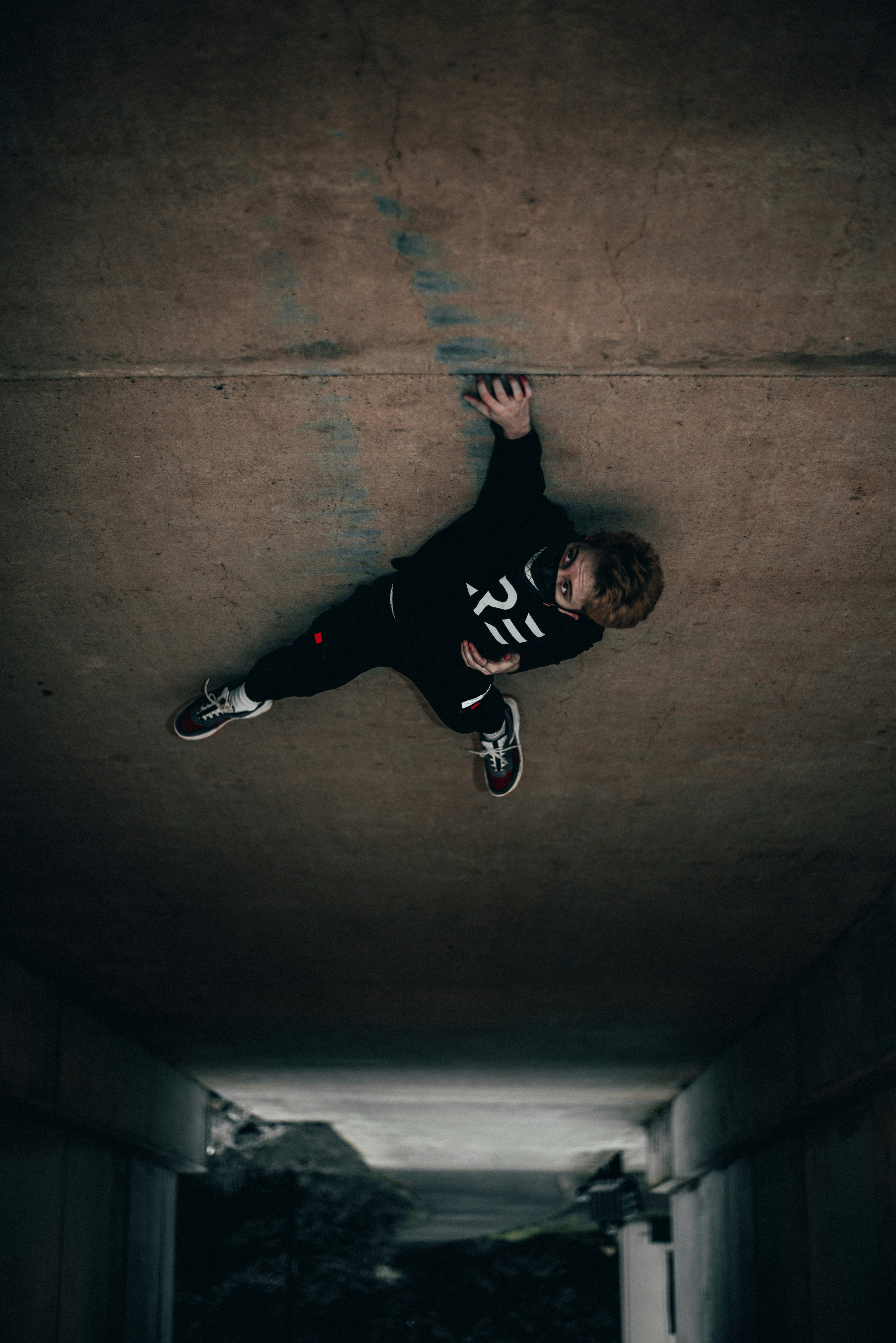 man in black and white long sleeve shirt and black pants lying on concrete floor