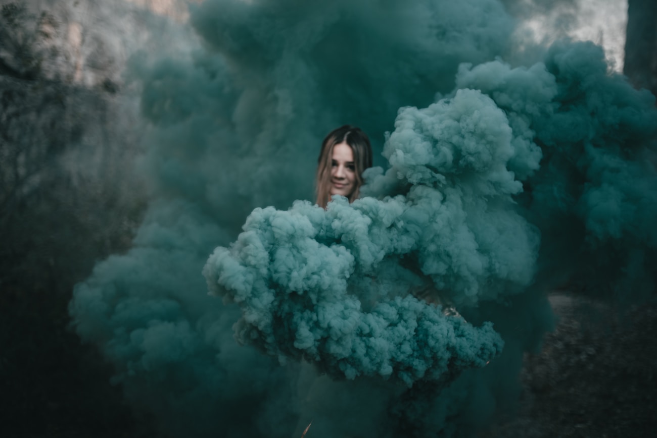 Woman posing with white smoke bomb for creative portrait photography