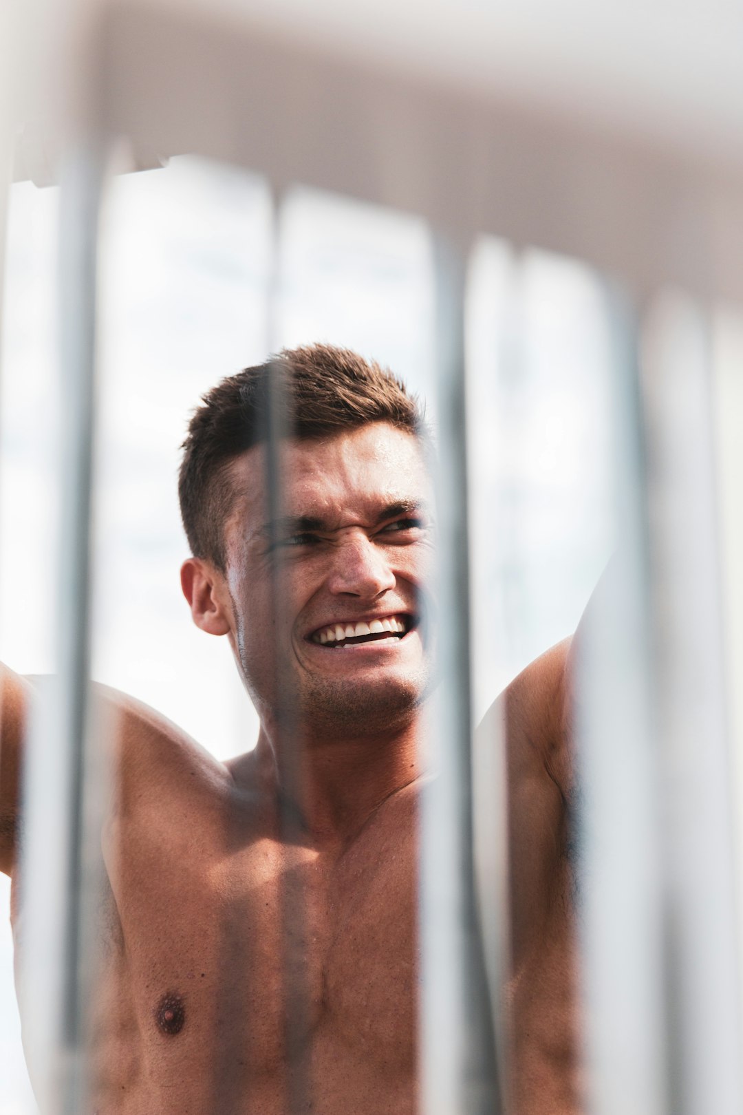 topless man smiling near window