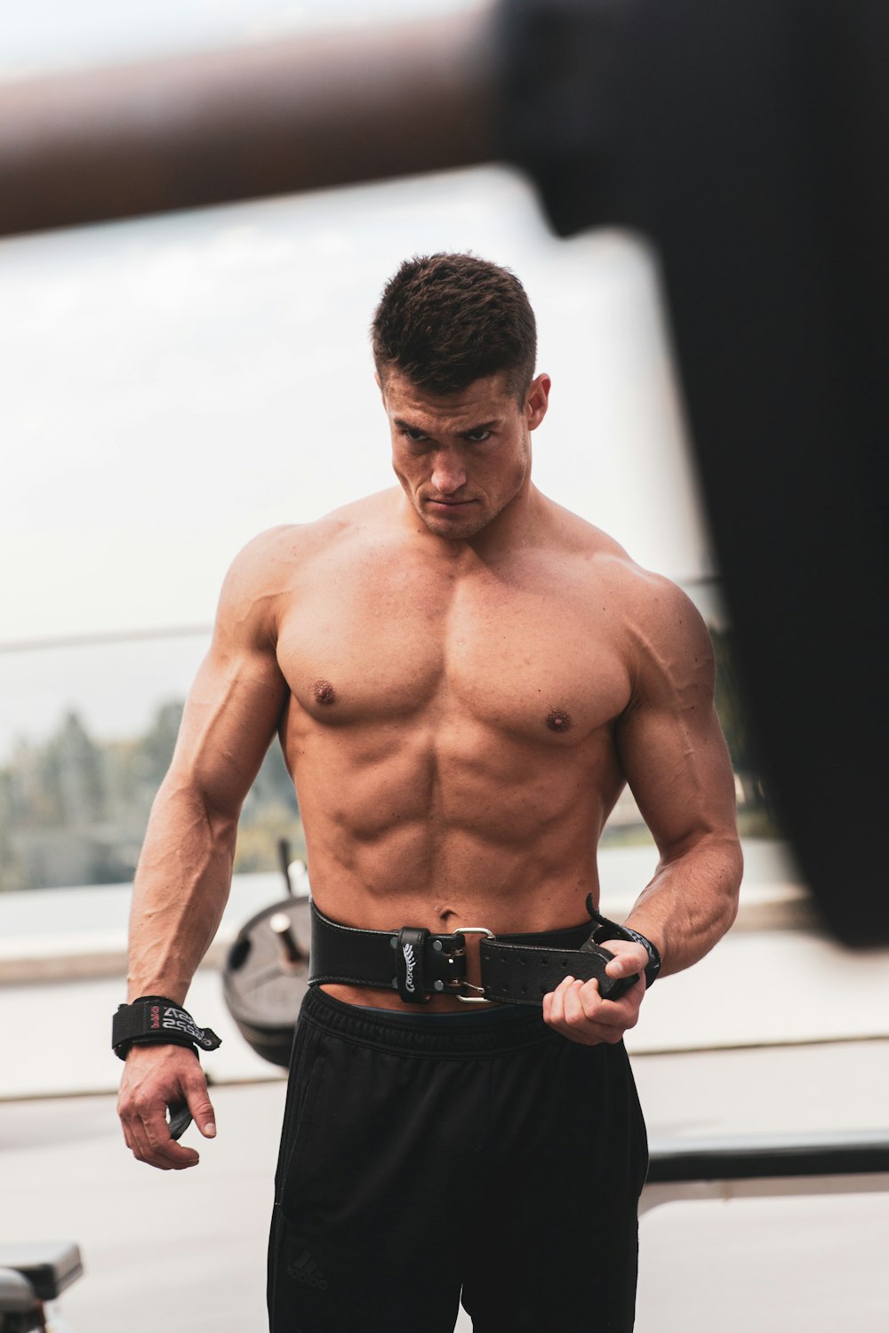 topless man in black shorts standing on white floor during daytime