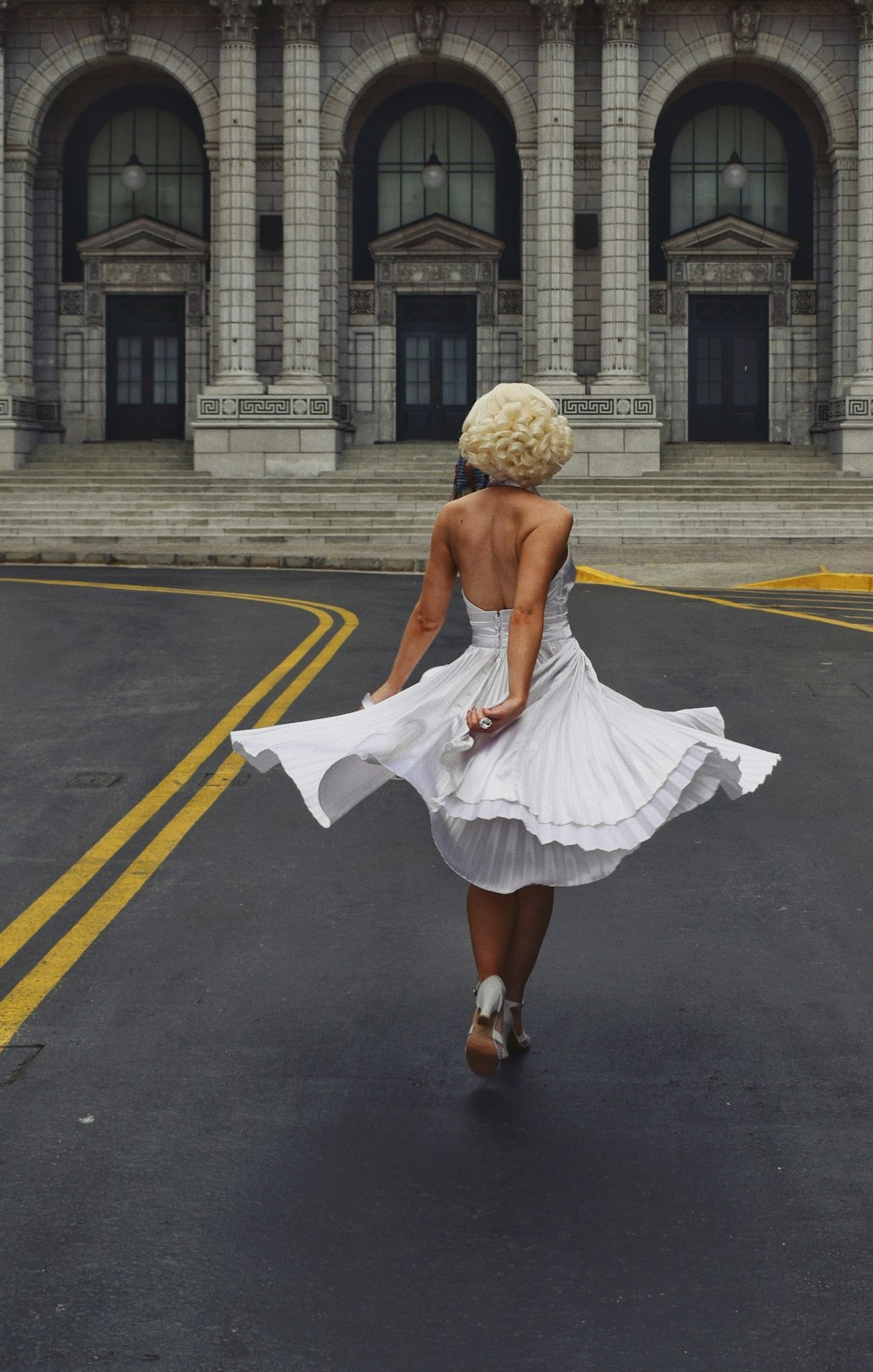 昼間の道路を歩く白いスカートの女性