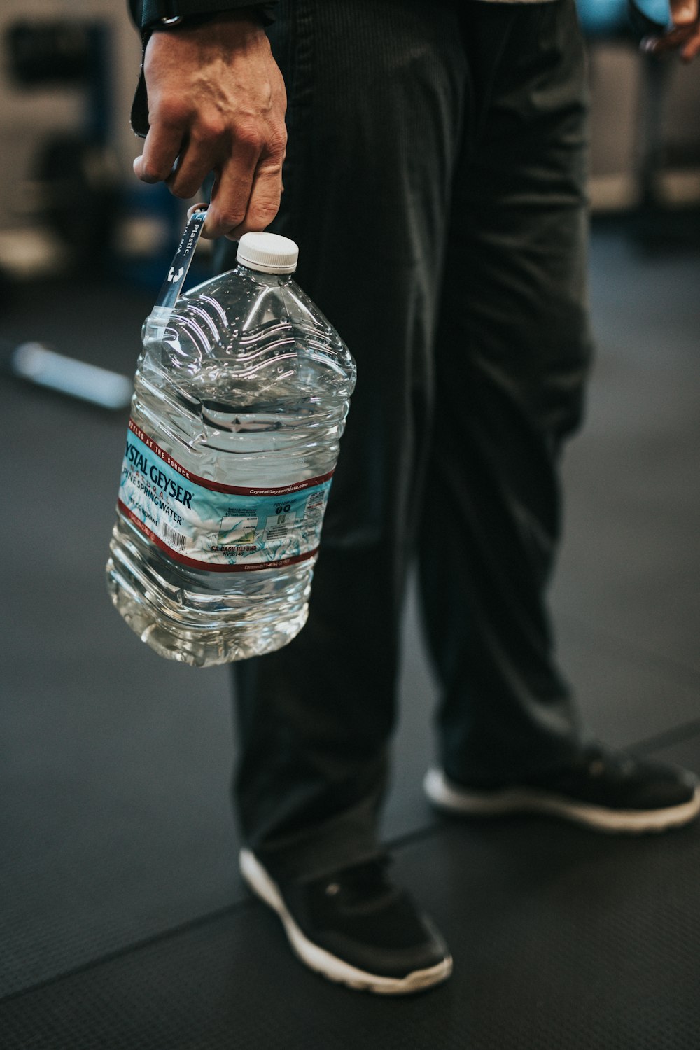 Persona che tiene in mano una bottiglia di plastica trasparente