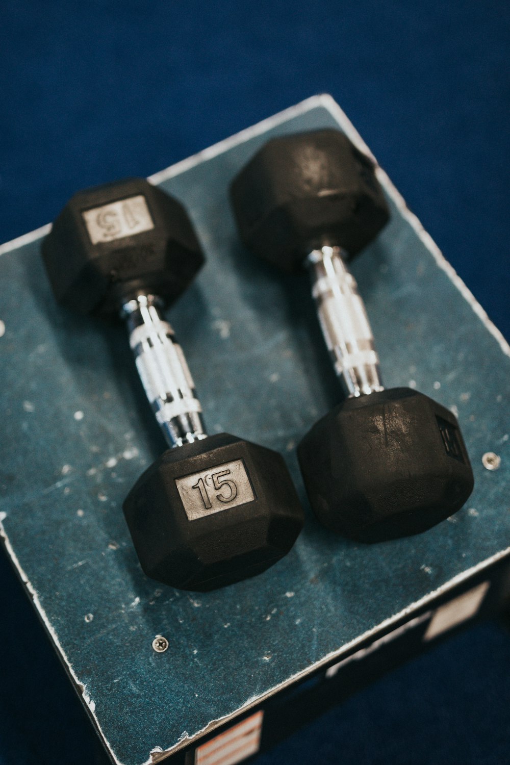 2 black dumbbells on blue textile