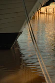 Close-up of the boat’s wooden details and ropes under bright daylight.