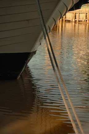 Close-up of the boat’s wooden details and ropes under bright daylight.