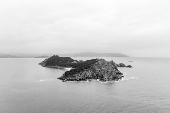 grayscale photo of mountain near body of water in Illas Cies Spain