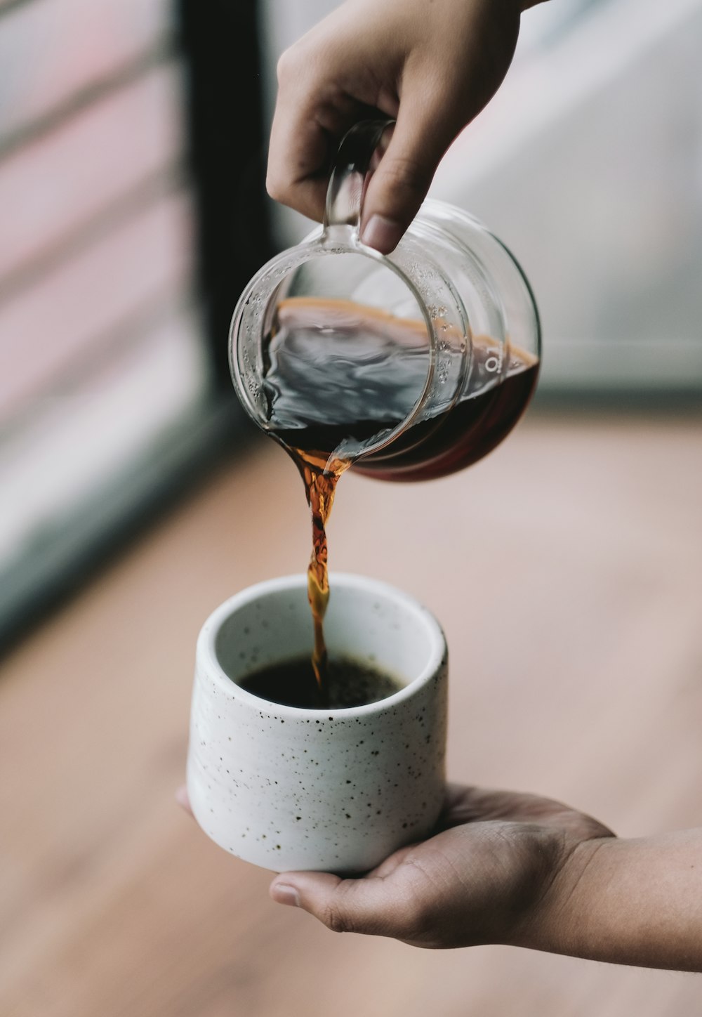 personne versant de l’eau sur une tasse en céramique blanche