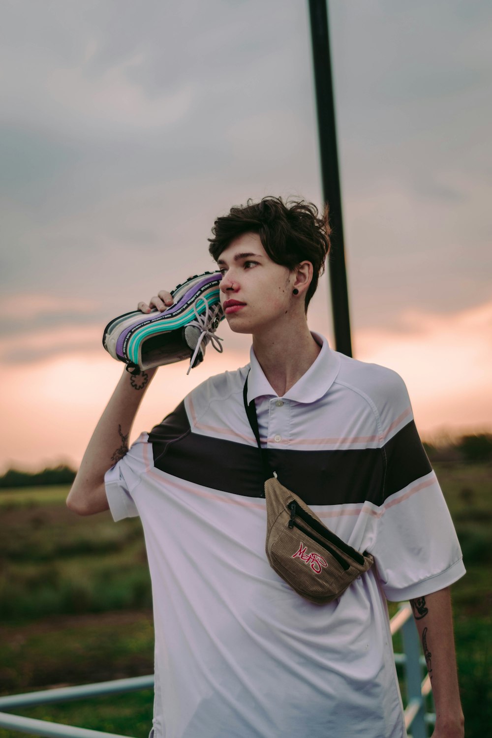 Hombre en camisa de punto blanco y negro sosteniendo mochila adidas en blanco y negro