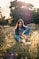 woman in blue denim jacket and blue denim jeans sitting on brown grass field during daytime