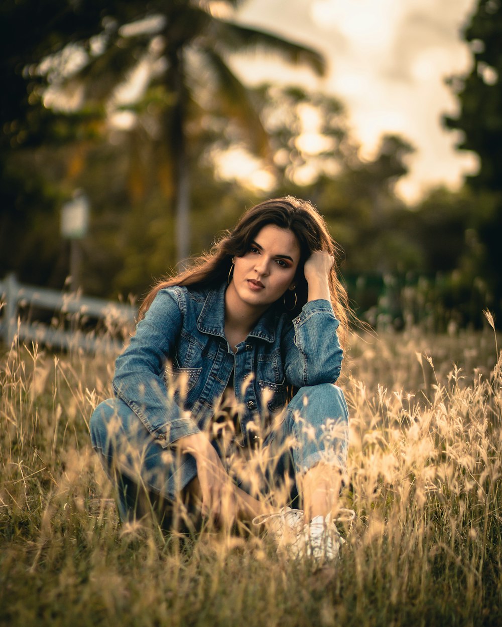 woman in blue denim jacket sitting on brown grass field during daytime