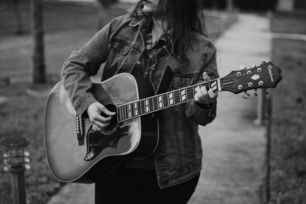 woman in denim jacket playing guitar