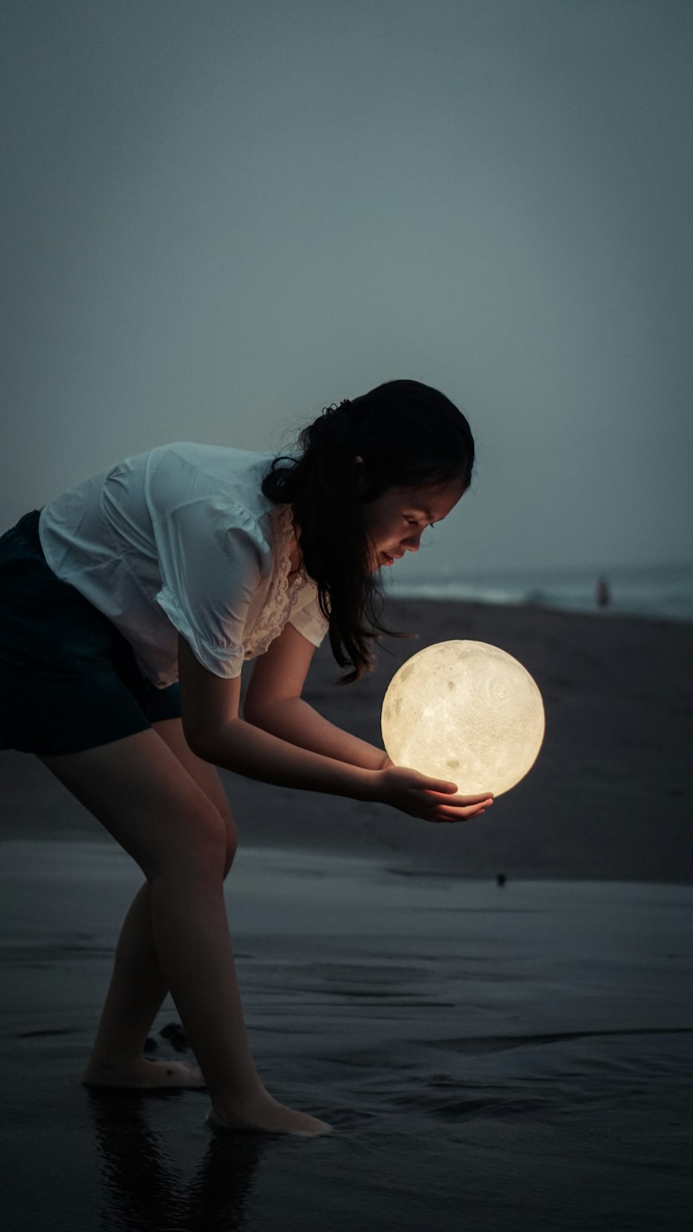 woman in blue shirt and black shorts holding white moon