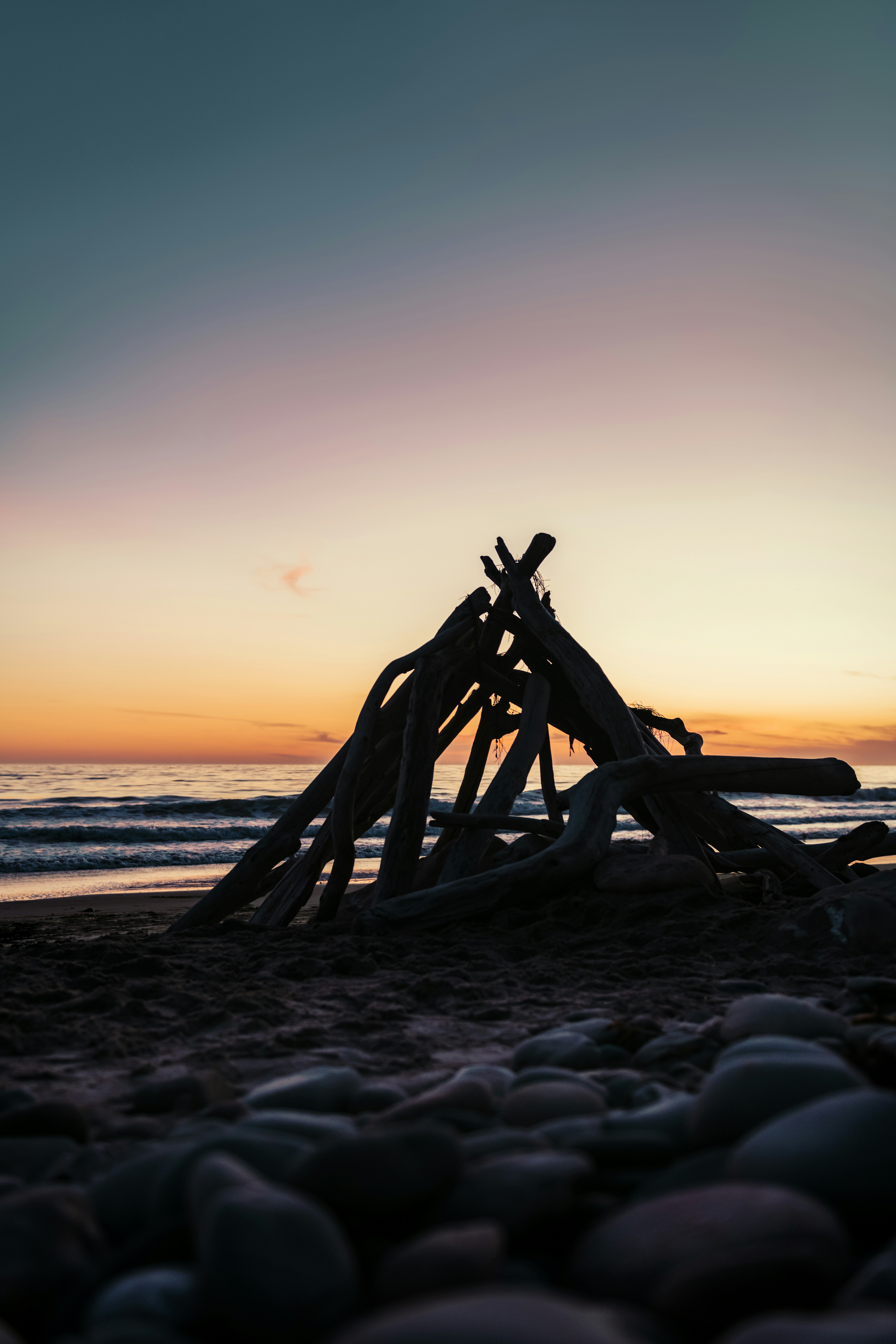 Brown wooden driftwood log resting on a beach at sunset