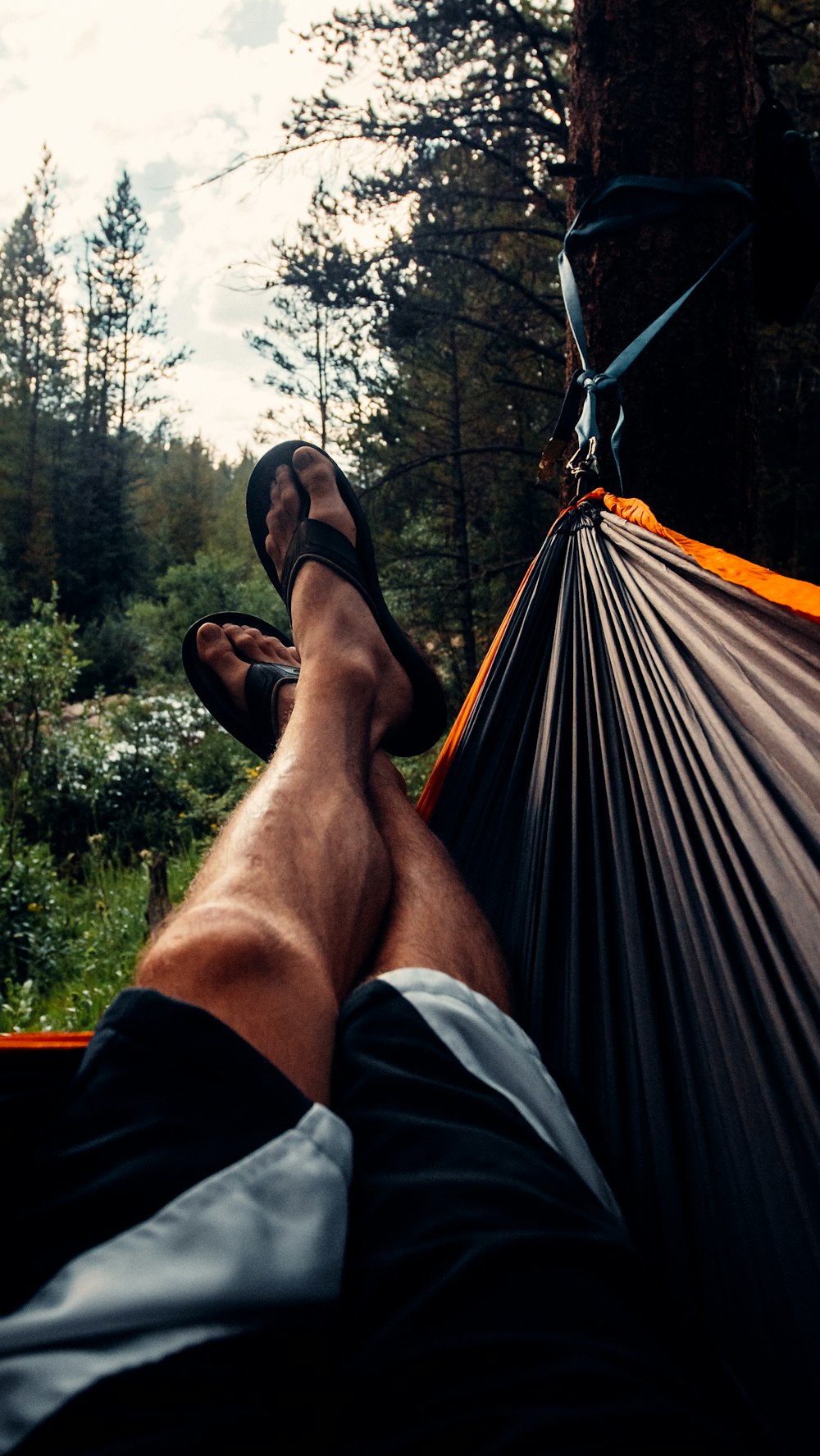 person wearing black flip flops lying on hammock