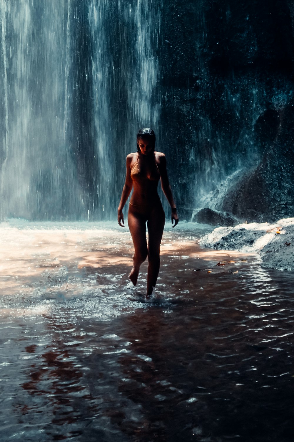 Frau im schwarzen Bikini steht tagsüber auf Wasserfällen