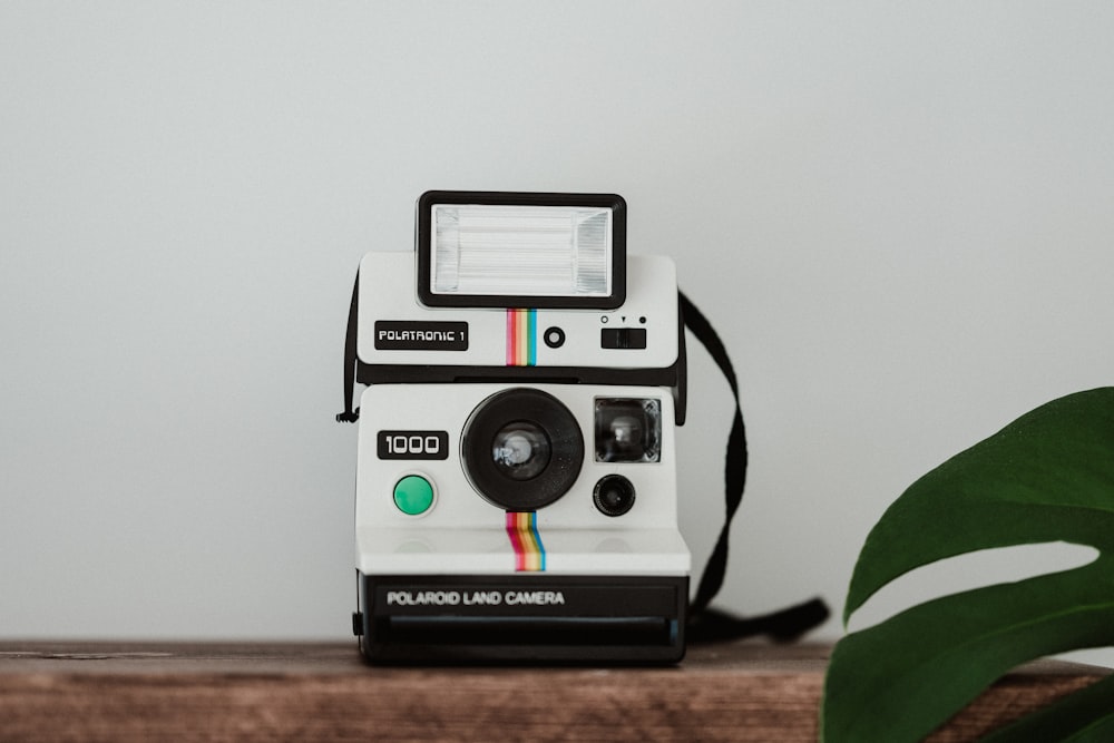 white and black polaroid camera on brown wooden table