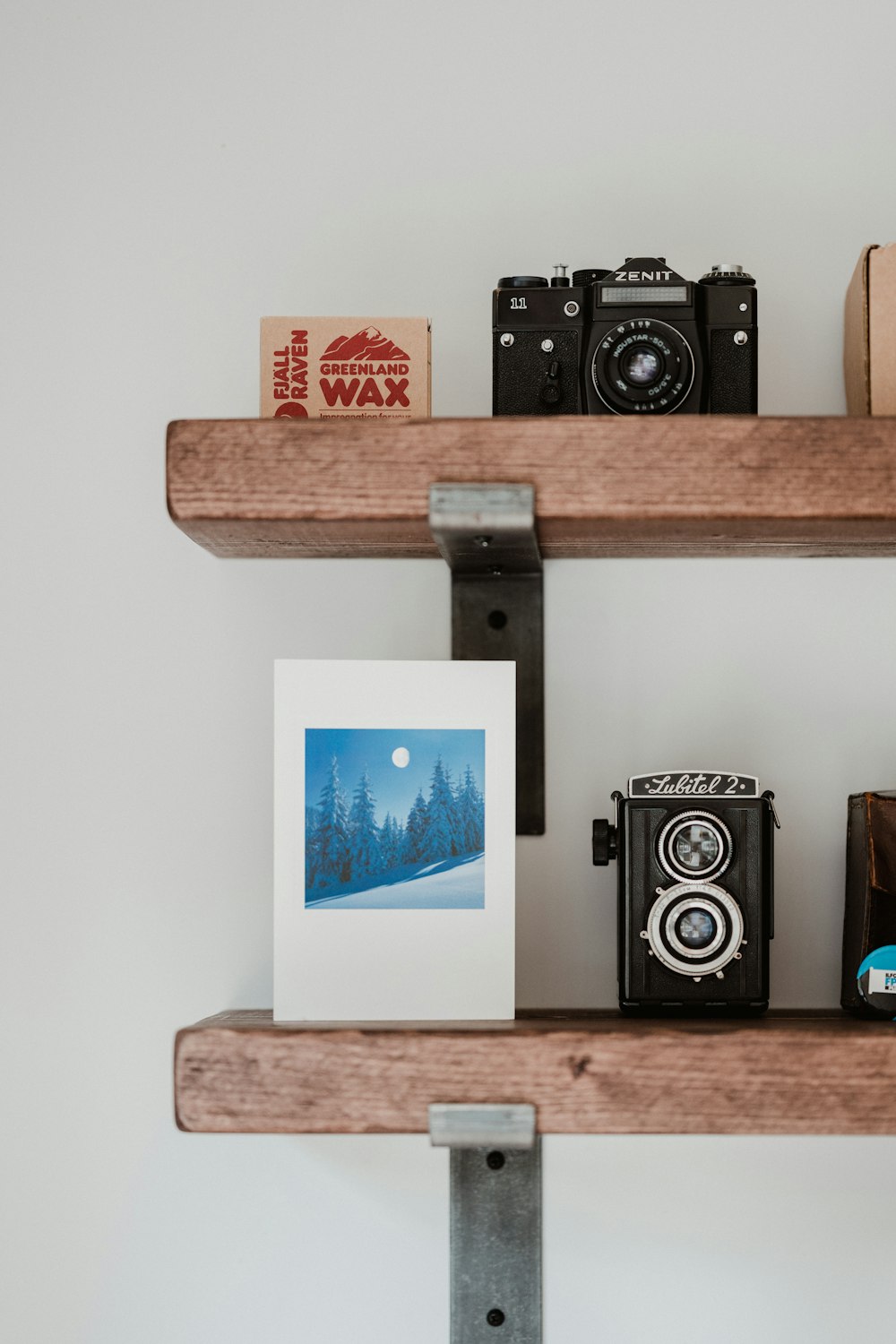 Fotocamera DSLR nera e argento su mensola a muro in legno bianco