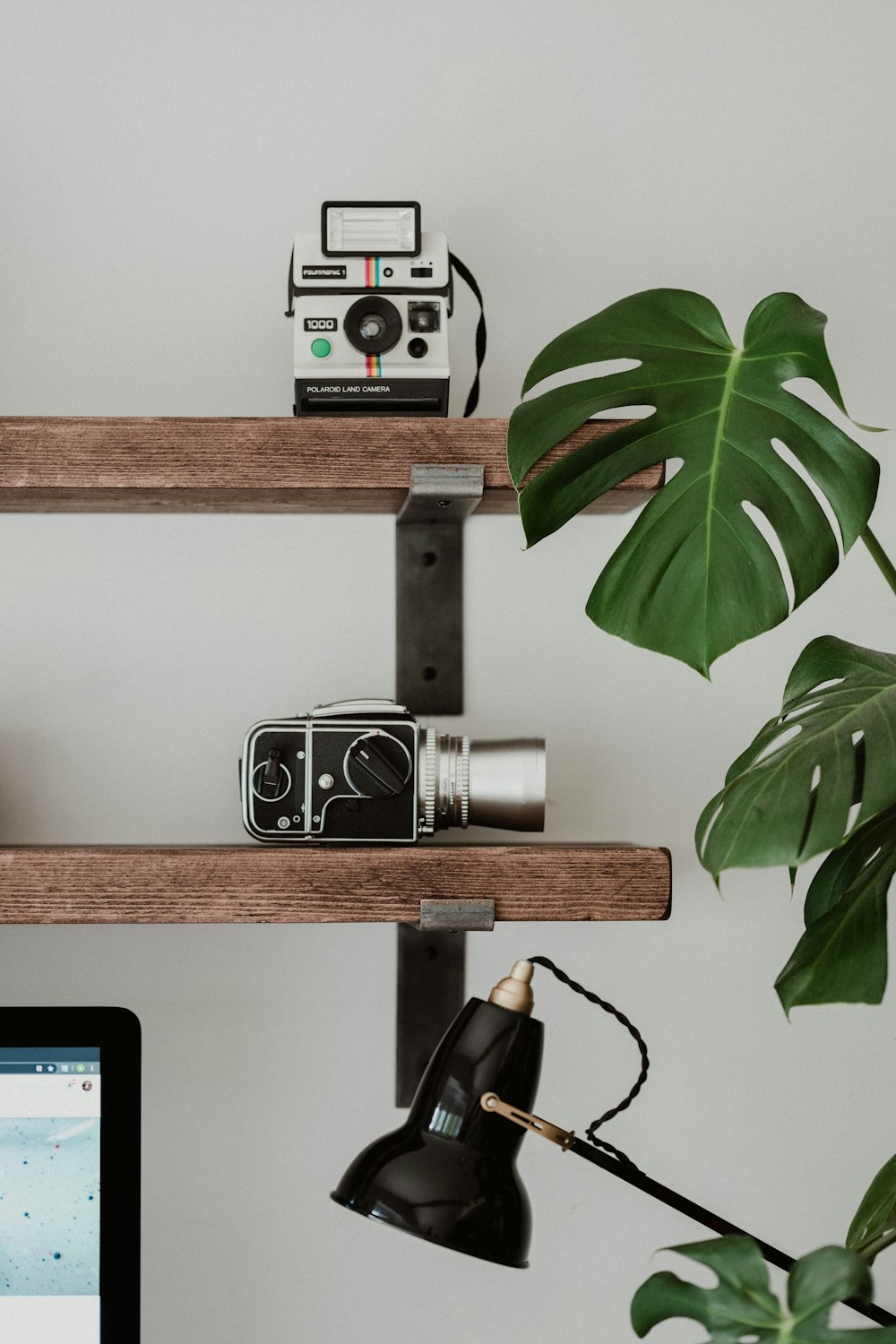 black and silver camera on brown wooden shelf