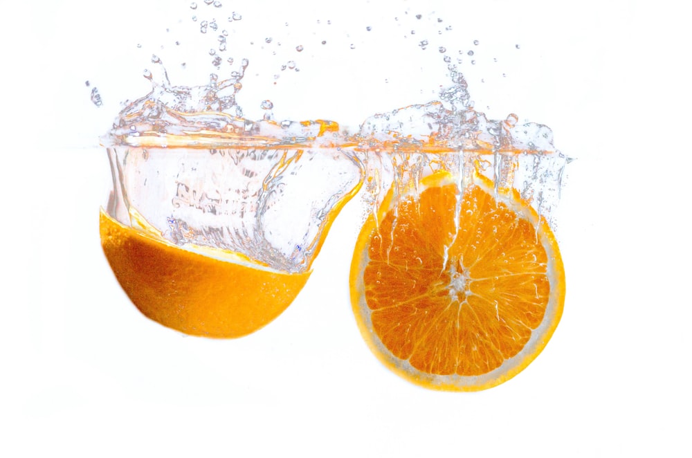 Frutta arancione in acqua con sfondo bianco
