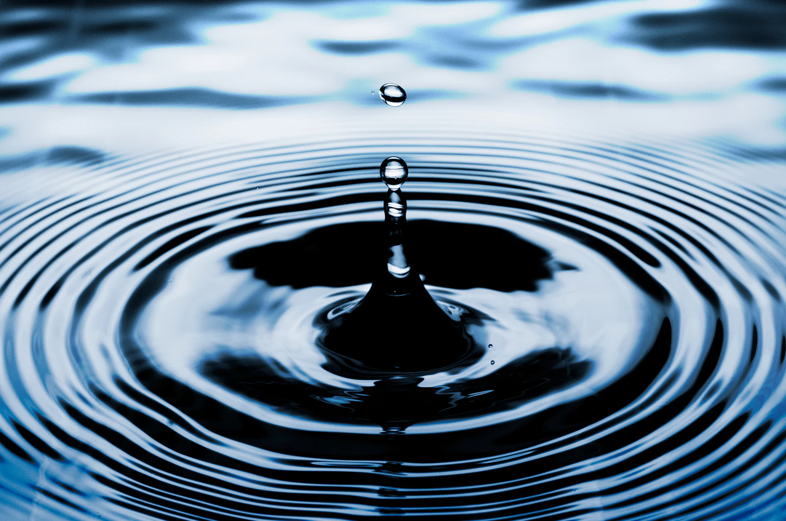 A single drop striking still water, rings travelling outward