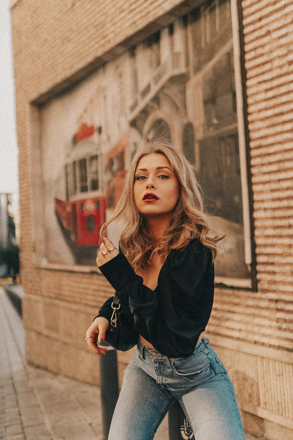 woman in black long sleeve shirt and blue denim jeans sitting on concrete stairs