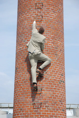 man in gray pants and black shoes standing on brown brick wall