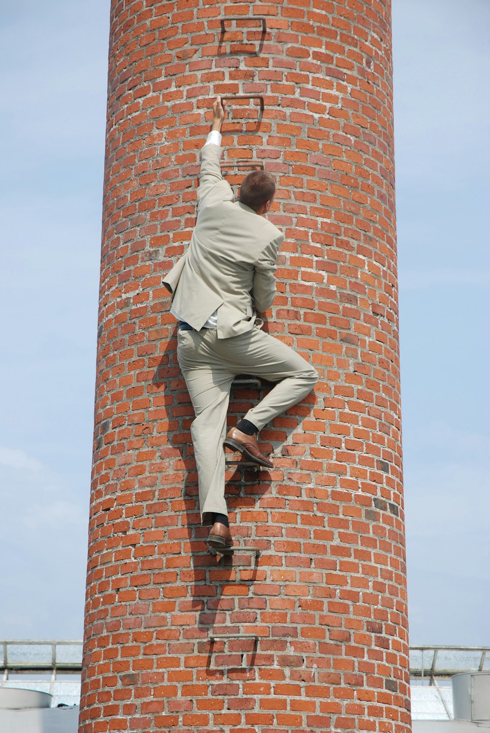 man in gray pants and black shoes standing on brown brick wall