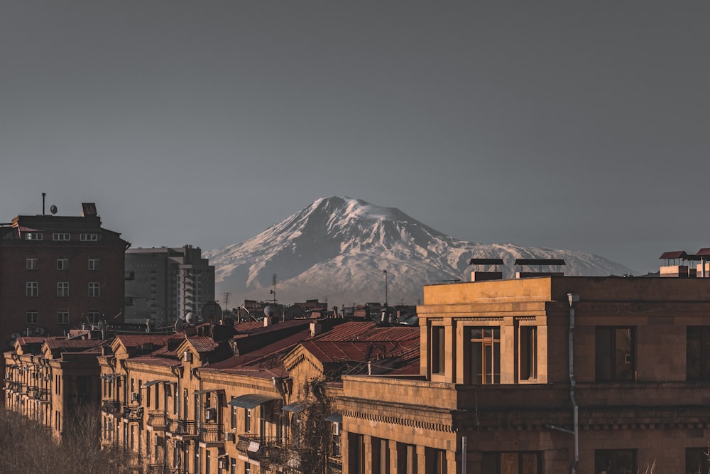 brown concrete building near snow covered mountain during daytime