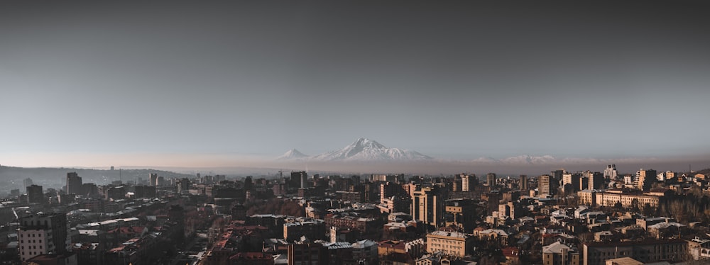 city with high rise buildings near snow covered mountain during daytime