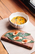 A vibrant bowl of steaming Creole gumbo garnished with fresh herbs on a rustic wooden table.