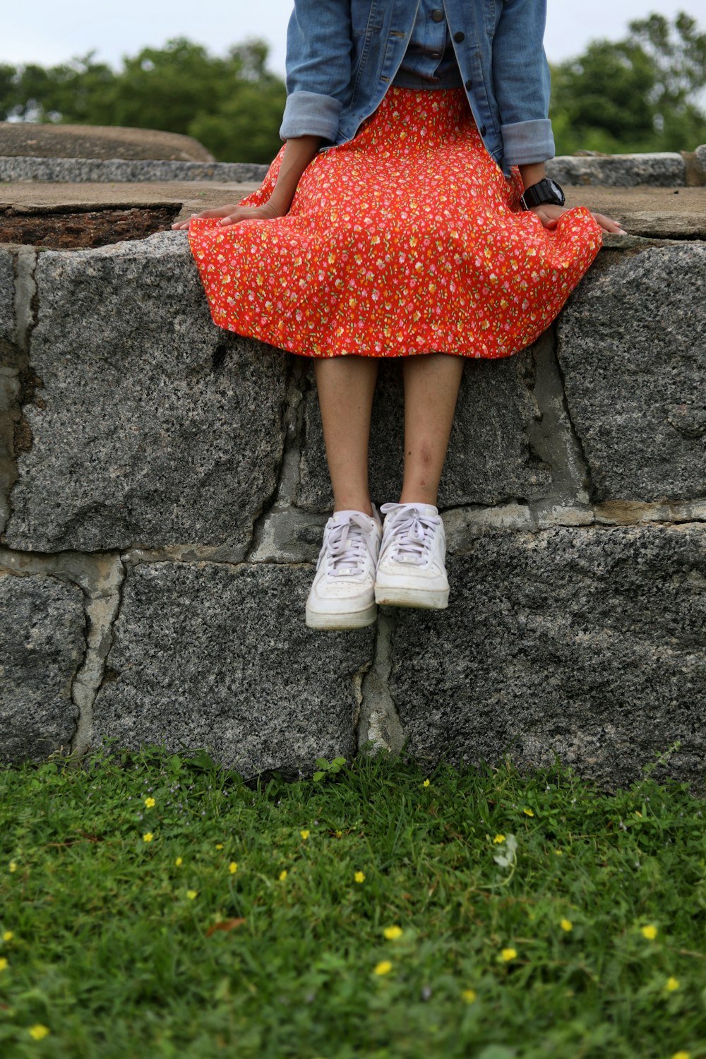 woman in red dress and white shoes standing on gray concrete stairs