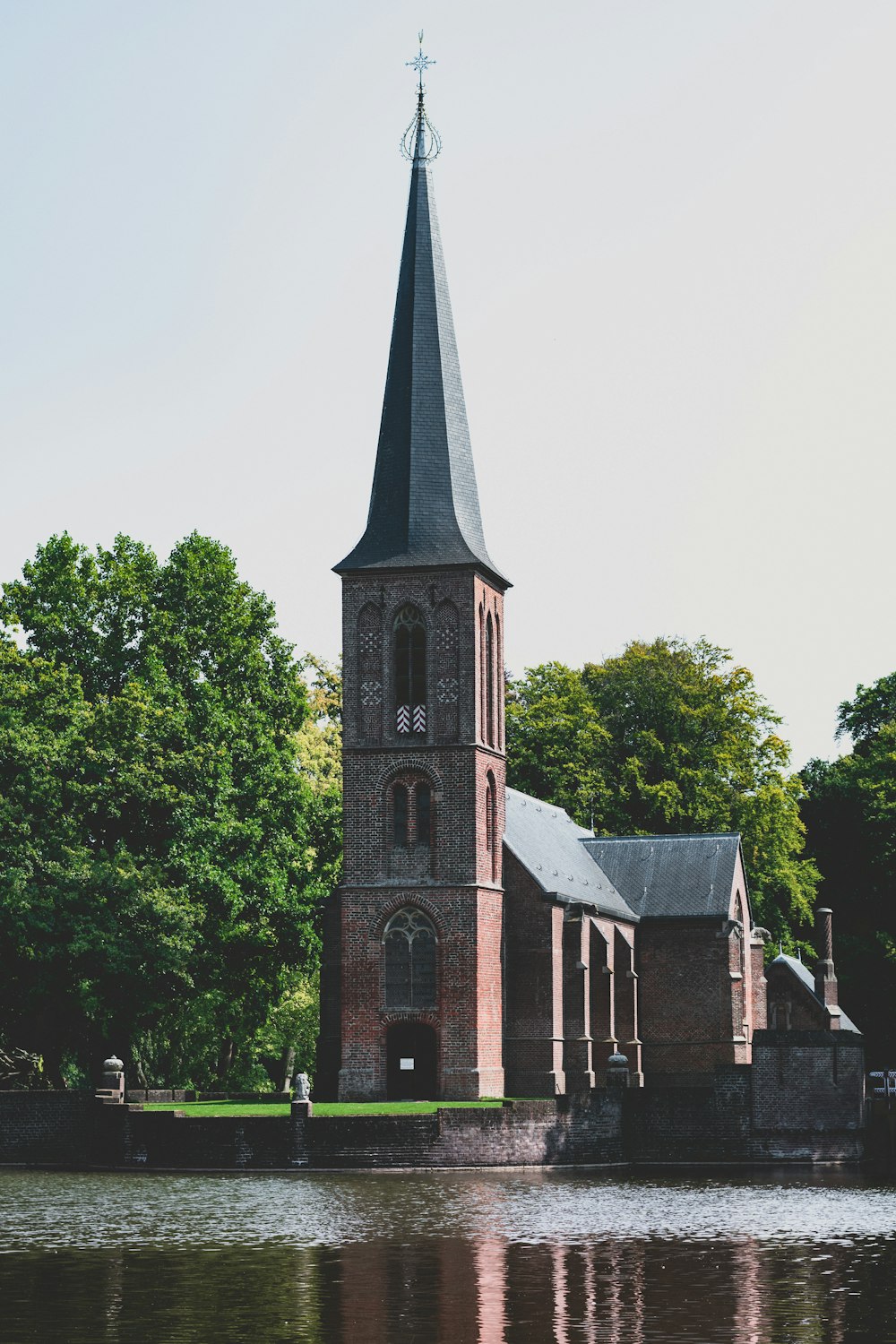 graue und schwarze Betonkirche in der Nähe von grünen Bäumen tagsüber